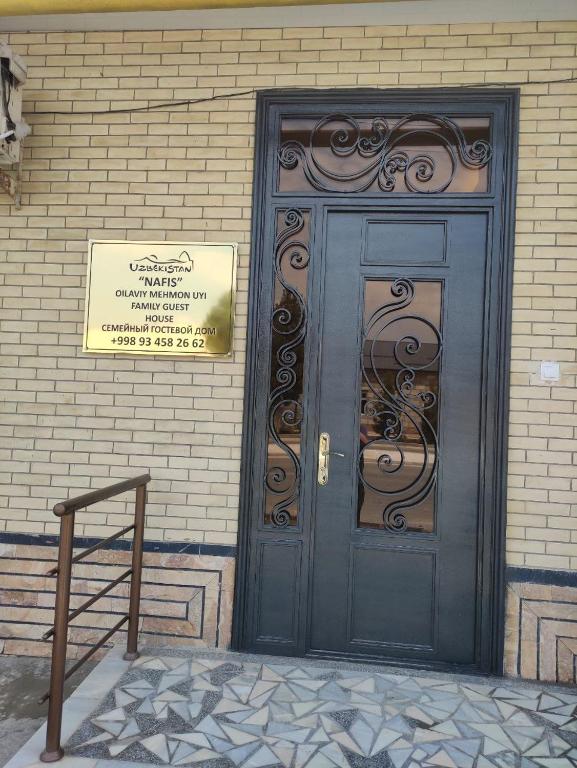 a black door on a brick building with a sign on it at Hostel Nafis in Bukhara
