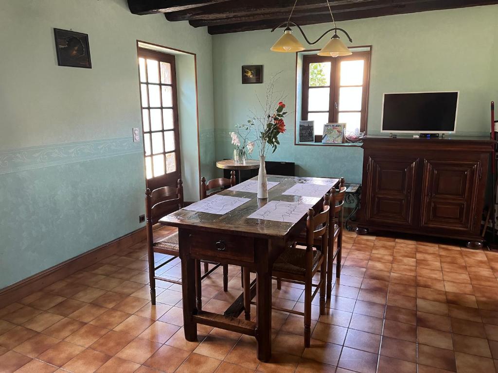 une salle à manger avec une table avec des chaises et une télévision dans l'établissement Petites maisons avec piscine, à Sarlat-la-Canéda