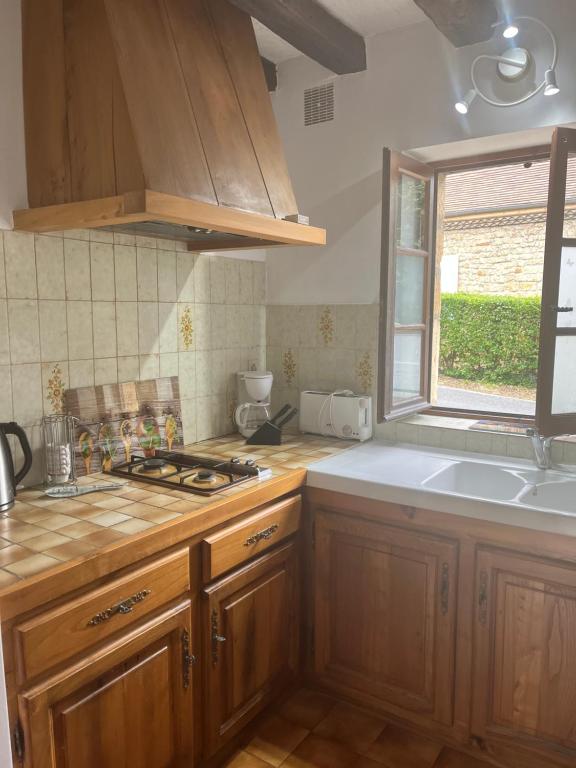 d'une cuisine avec des placards en bois, un évier et une fenêtre. dans l'établissement Petites maisons avec piscine, à Sarlat-la-Canéda