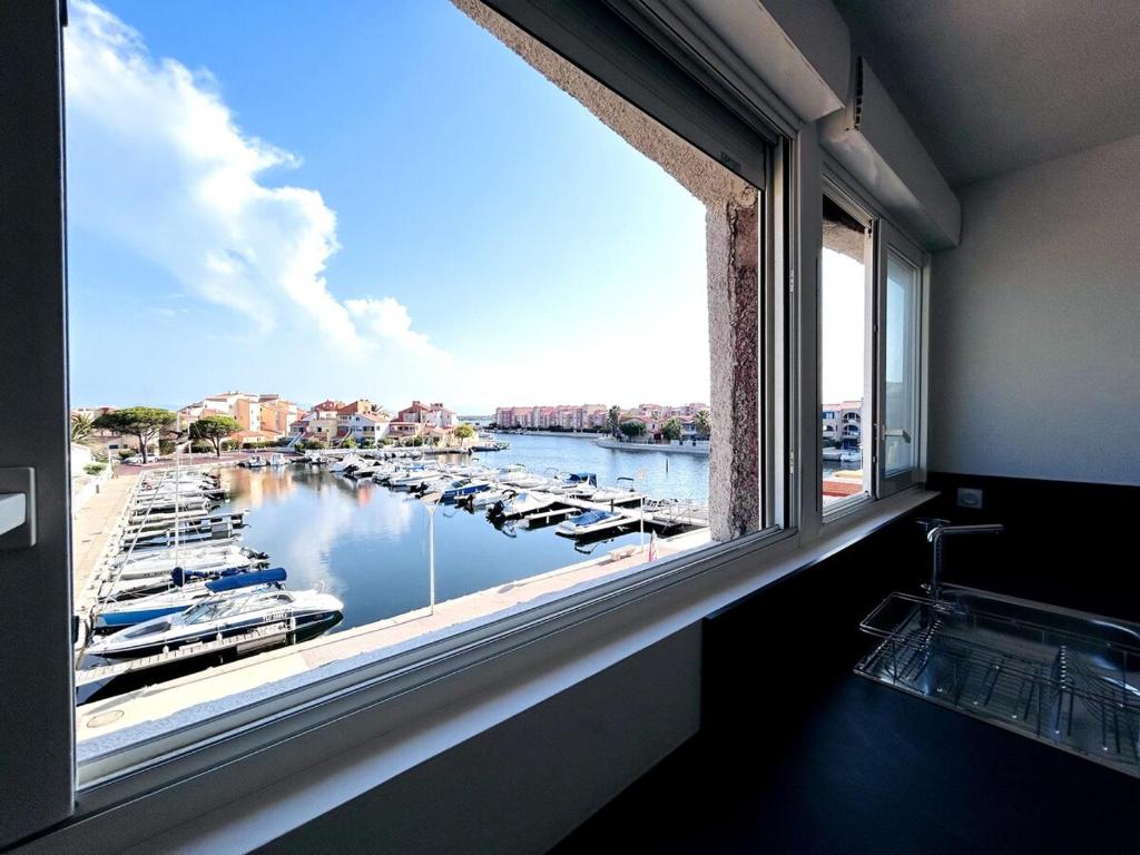 une grande fenêtre avec vue sur le port de plaisance dans l'établissement MAGNIFIQUE, GRAND ET MODERNE T3, PISCINE, WIFI, CLIM, VUE ET EMPLACEMENT SUPERBES, Coudalère, au Barcarès