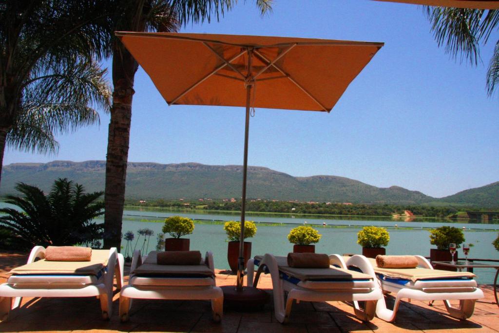 a group of lounge chairs and an umbrella and water at The Blue Crane Villa in Hartbeespoort