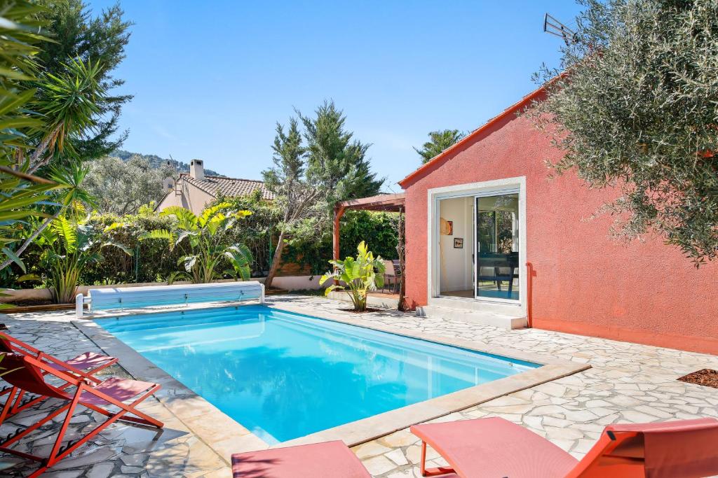 - une piscine en face d'une maison rouge avec des chaises dans l'établissement Villa Moderne avec Piscine Privée, à La Crau