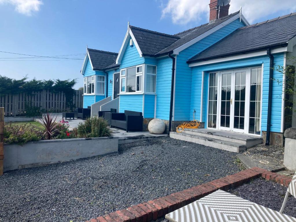 a blue house with a gravel driveway at Blue Lodge - by the sea, sauna, BBQ, private garden and parking in Aberystwyth