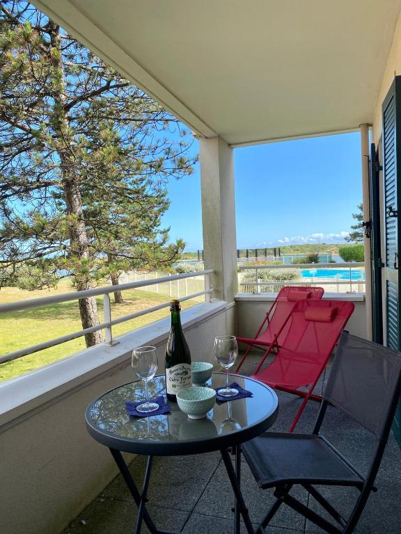 - une table avec 2 chaises et une bouteille de vin sur le balcon dans l'établissement Appartement 3 personnes Cabourg-Port Guillaume, à Dives-sur-Mer
