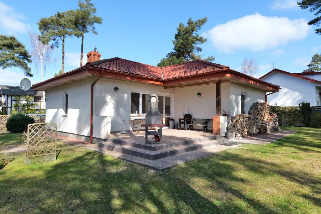 a small white house with a staircase in the yard at Słoneczny Dom in Poddąbie