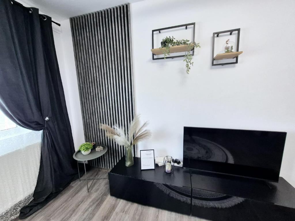 Una sala de estar con un televisor y una mesa. en Christal Apartment, en Bacău