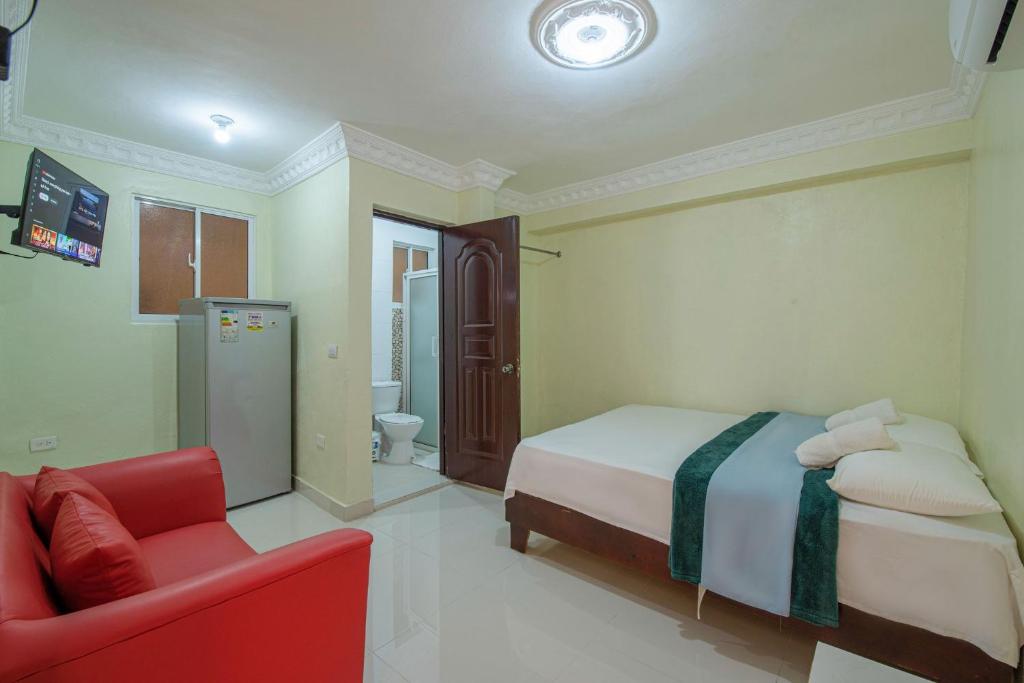 ein Schlafzimmer mit einem Bett und einem roten Stuhl in der Unterkunft Premium Single Room in Corales del Sur, Santo Domingo Este - Ole Las Americas in La Viva