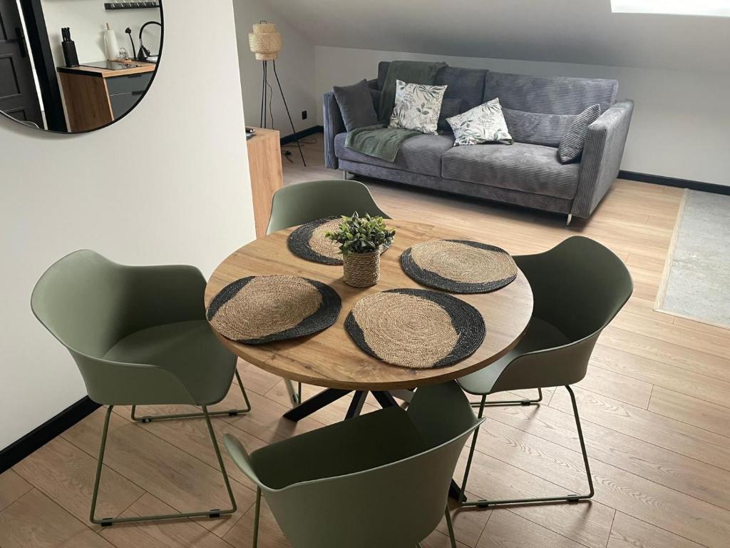 a dining room table with chairs and a couch at Harmony House -Appartement Green in Kołczewo