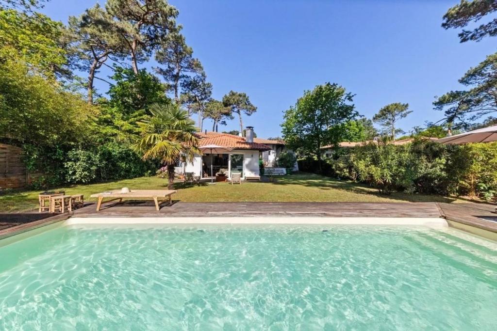 une piscine devant une maison dans l'établissement Villa bohème chic avec piscine & jardin au Pyla, à La Teste-de-Buch