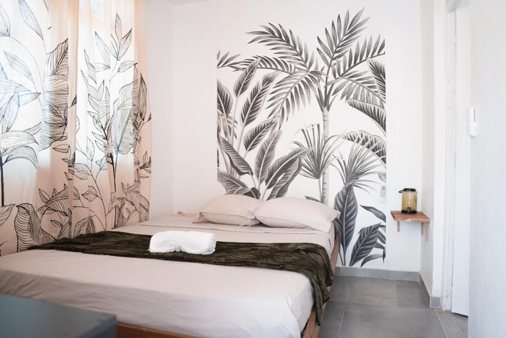 a bedroom with a bed with a mural of palm trees at La Kaz and Ti Thano in Port-Louis