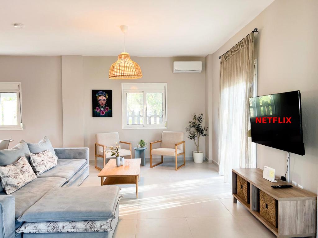 a living room with a couch and a tv at Casa De Vara in Nea Potidaea