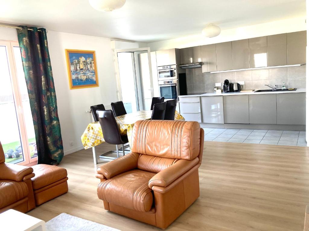 Il comprend un salon doté d'un canapé et d'une chaise ainsi qu'une cuisine. dans l'établissement Appartement 90m2, 3 chambres, 6 personnes, proche Paris, à Asnières-sur-Seine