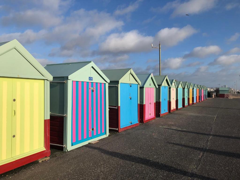 a row of colorful beach huts parked in a row at Bright and Spacious 2BR Maisonette Sleeps 8, Game Room, 5 mins to Brighton Beach and City Centre in Brighton & Hove