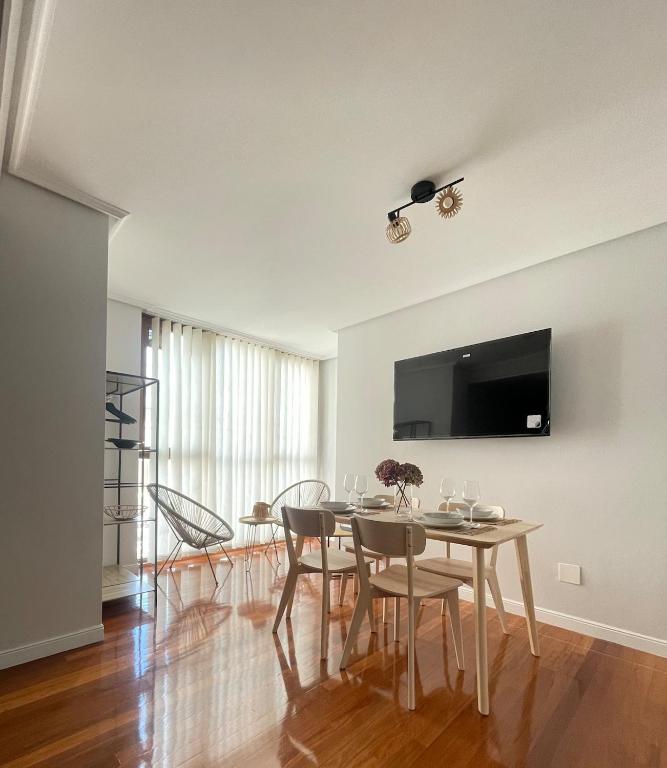 a dining room with a table with chairs and a flat screen tv at Marismas de Cantabria cerca de Laredo in Bádames