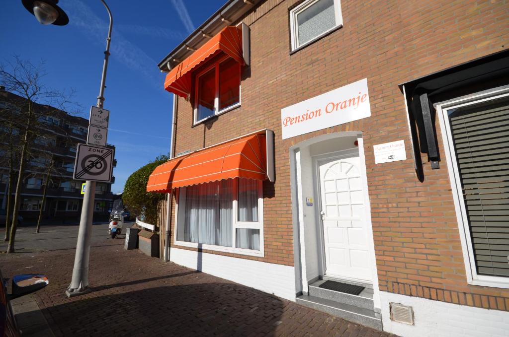 un bâtiment en briques avec un auvent orange dans une rue dans l'établissement Pension Oranje, à Zandvoort