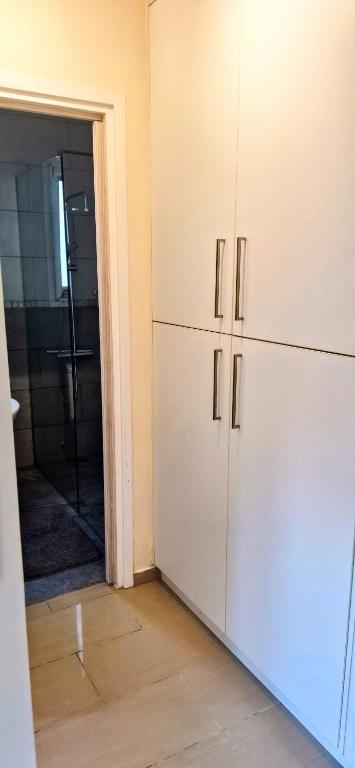 a kitchen with white cabinets and a door to a bathroom at AFRODITI APARTMENTs in Perivolia