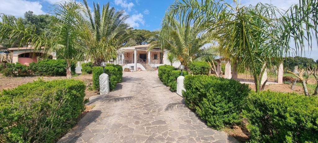 een loopbrug naar een huis met palmbomen bij Villa Virginia Porto Pino in Porto Pino