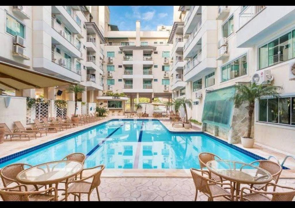 a swimming pool with tables and chairs next to a building at Apartamento 207 varias piscinas in Bombinhas