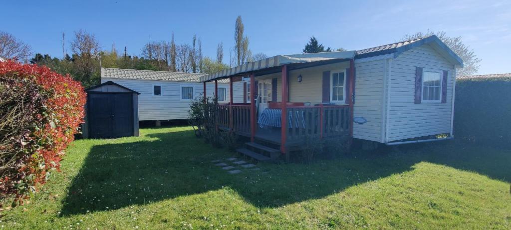a tiny house in a yard next to a fence at Mobil home 4 à 6 pers camping 5 étoiles proche Deauville in Saint-Arnoult