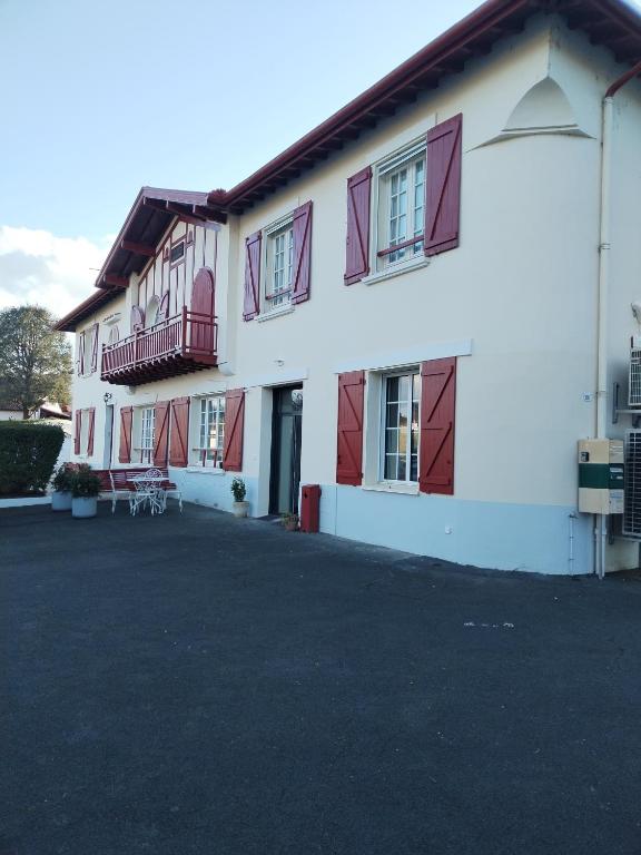 - un grand bâtiment blanc avec des fenêtres à volets rouges dans l'établissement Gîte classé 4 étoiles Mulhoa, à Hasparren
