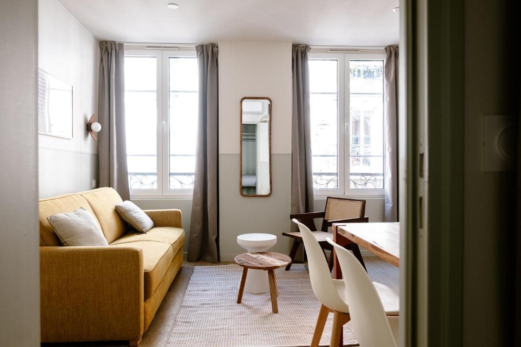 ein Wohnzimmer mit einer Couch und einem Tisch und Stühlen in der Unterkunft Babylon Popincourt in Paris