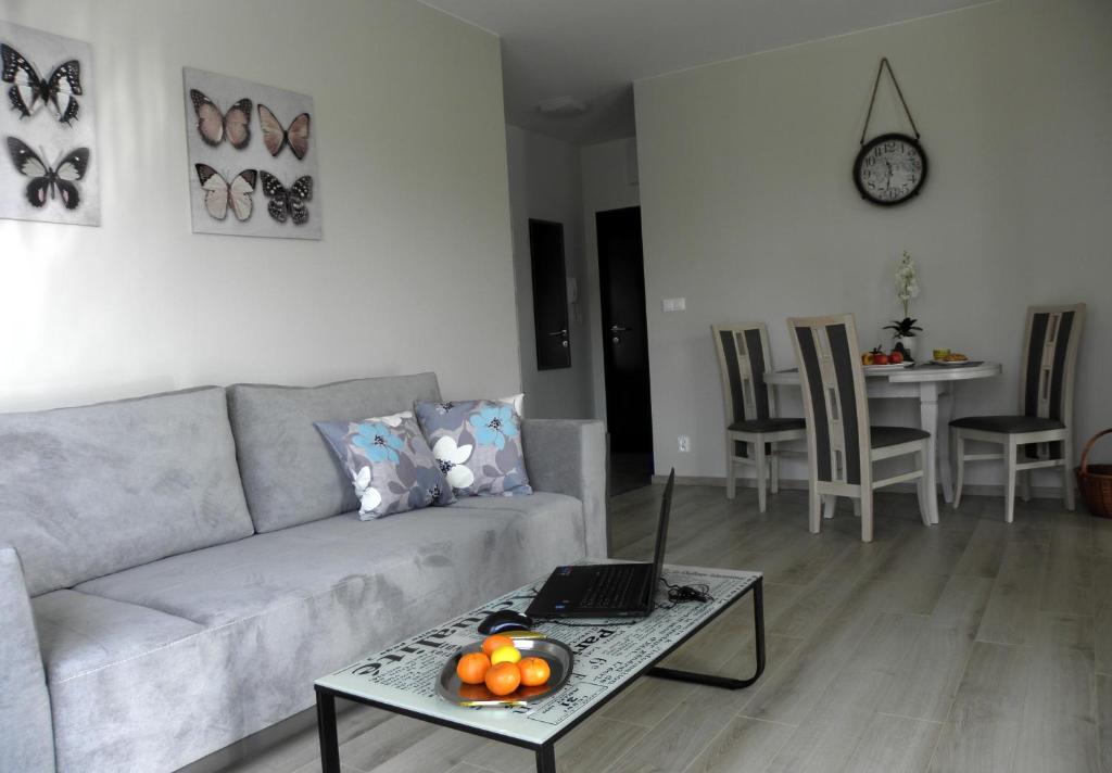 sala de estar con sofá y mesa con ordenador portátil en Novum Arkadia Apartamenty en Varsovia