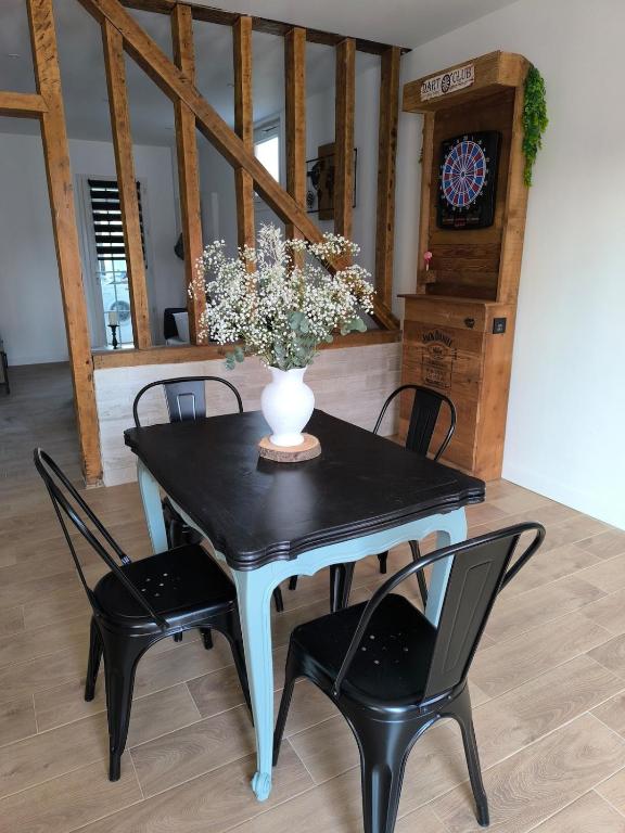 - une table à manger avec un vase orné de fleurs dans l'établissement L'Eucalyptus, à Saint-Nicolas-dʼAliermont