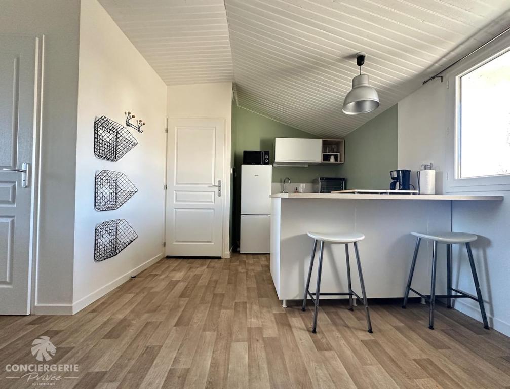 une cuisine avec deux tabourets de bar et un comptoir dans l'établissement Confortable studio proche mer et ville, à La Tremblade