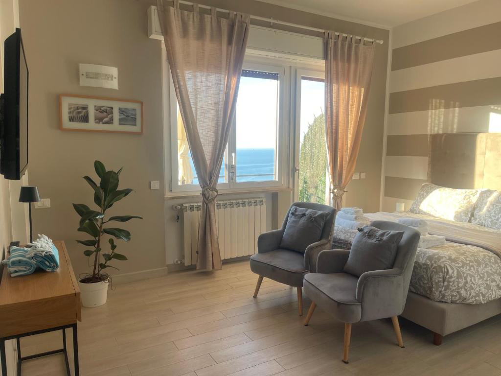 ein Schlafzimmer mit einem Bett und zwei Stühlen und einem Fenster in der Unterkunft UN SOGNO NEL GOLFO DEI POETI in Lerici
