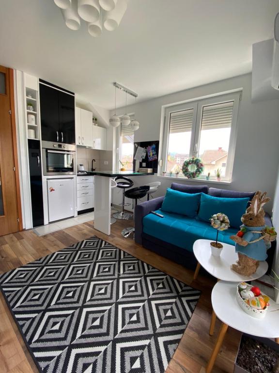 een woonkamer met een blauwe bank en een keuken bij URBANIC Apartment in Vrnjačka Banja