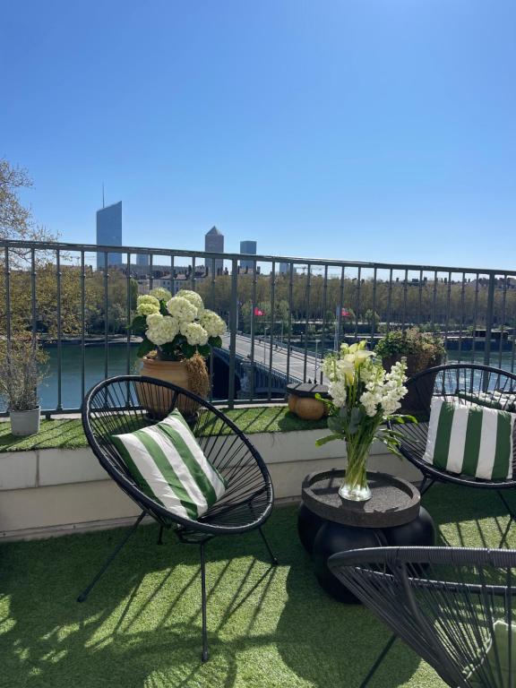 - un balcon avec 2 chaises et une table fleurie dans l'établissement Coeur de Lyon avec Terrasse et Jacuzzi, à Lyon