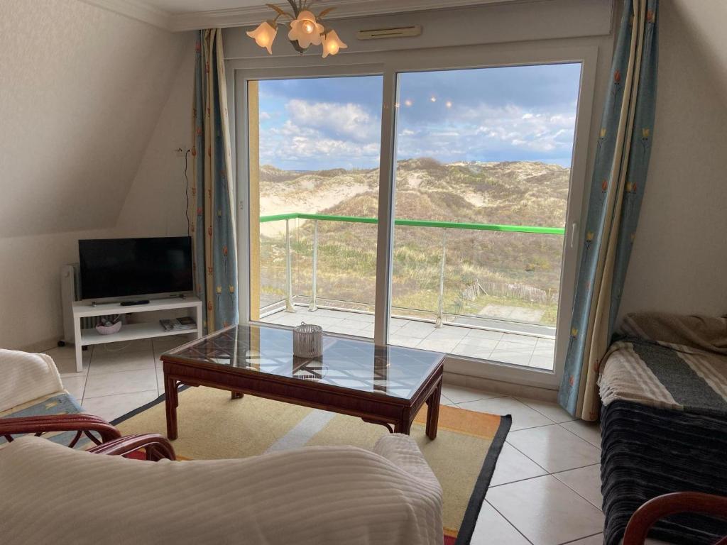 a living room with a glass table and a large window at Escapade Sarah, appartement duplex in Fort-Mahon-Plage