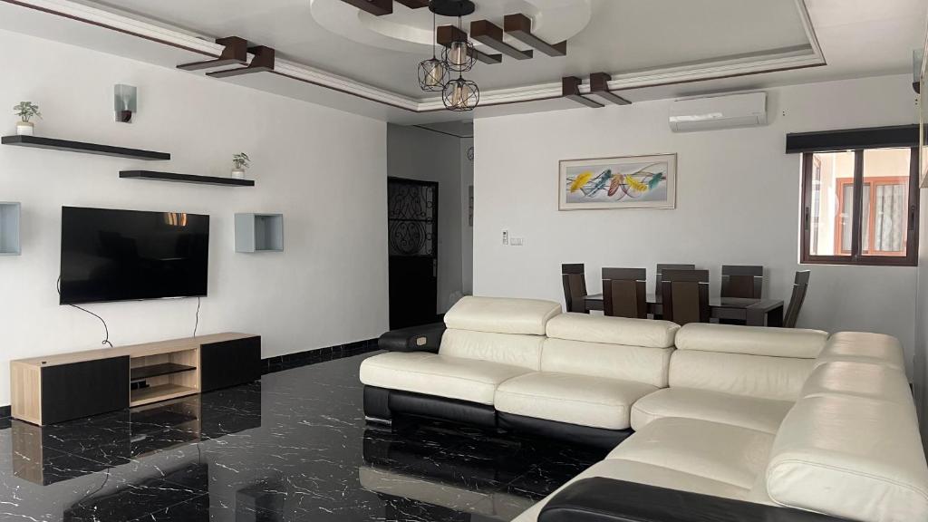 a living room with white furniture and a flat screen tv at Résidence Belle Alliance in Yaoundé