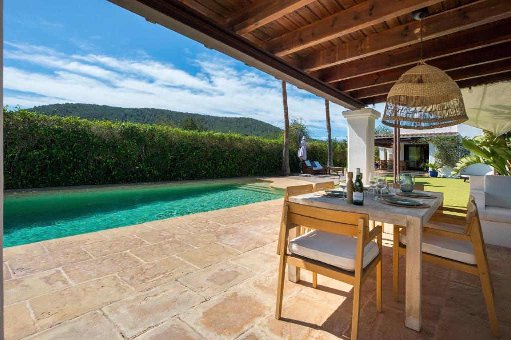a patio with a table and chairs and a pool at Can Botanic in Sant Josep de sa Talaia