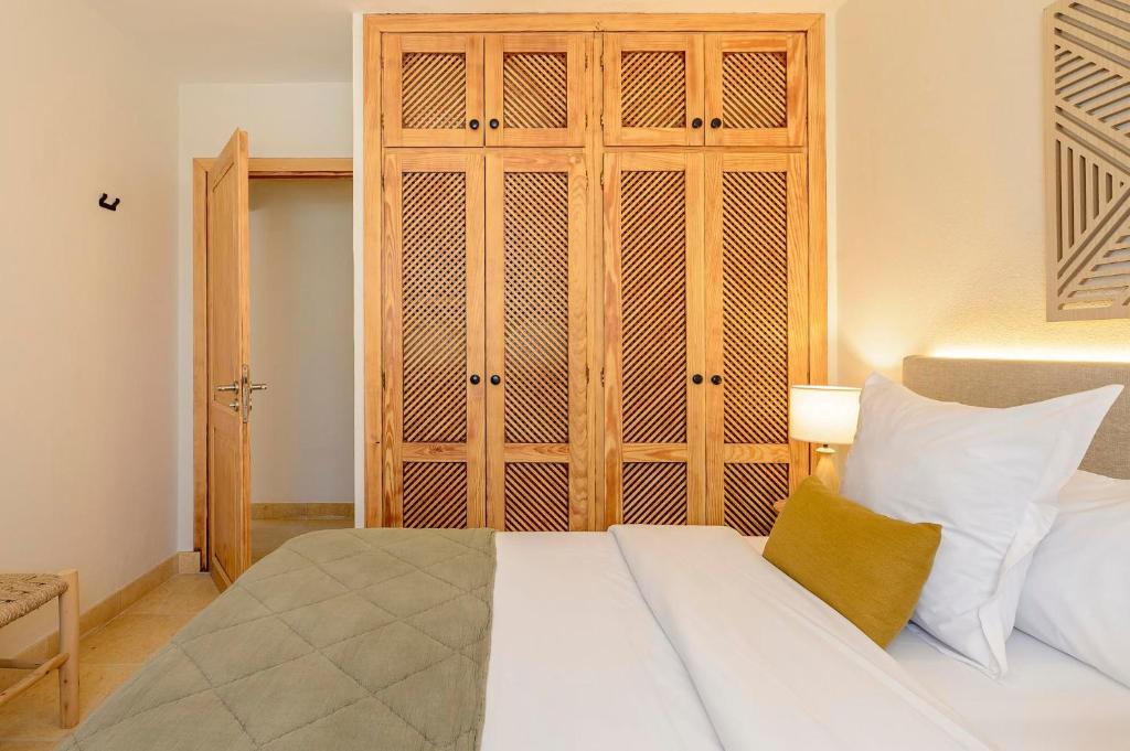 a bedroom with a white bed and a wooden cabinet at Can Botanic in Sant Josep de sa Talaia