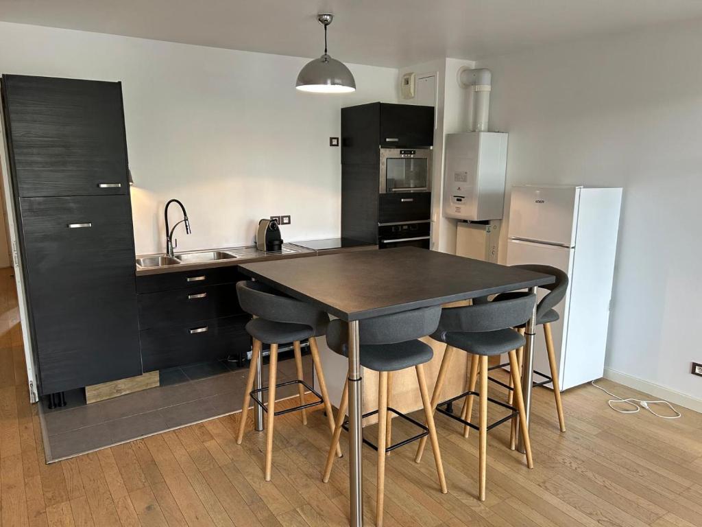 - une cuisine avec une table noire et des tabourets dans l'établissement Arcachon Centre et Plage, à Arcachon