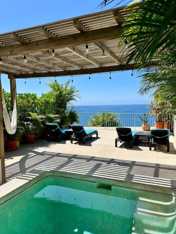 a swimming pool with a pergola and a table and chairs at Ocean View Apartment PXM in Puerto Escondido
