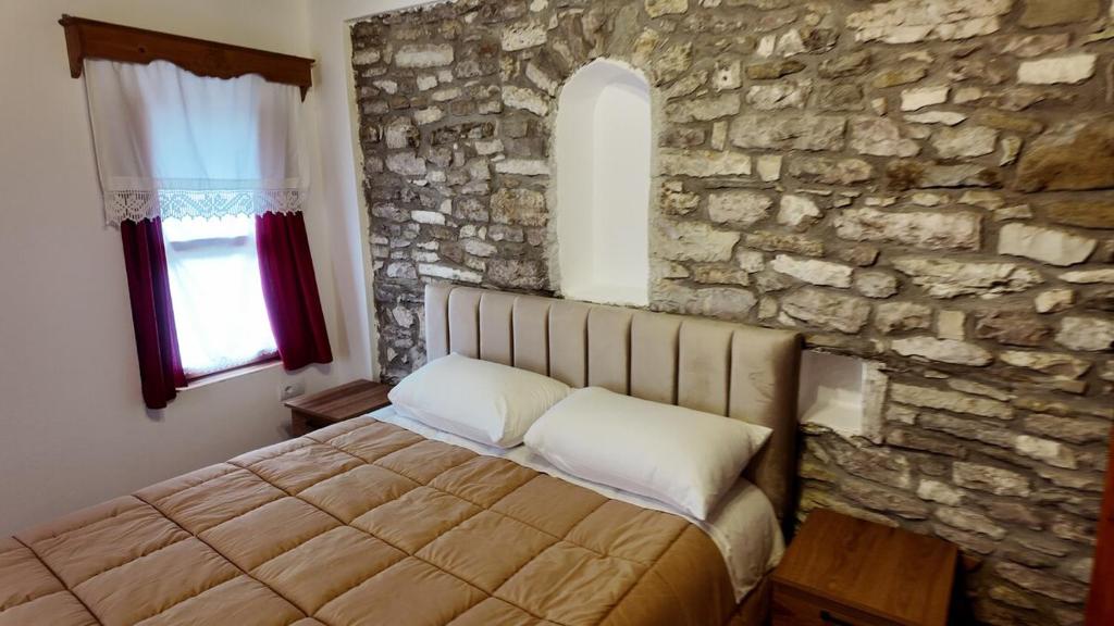 a bedroom with a bed in a stone wall at Suite of Bazaar in Gjirokastër