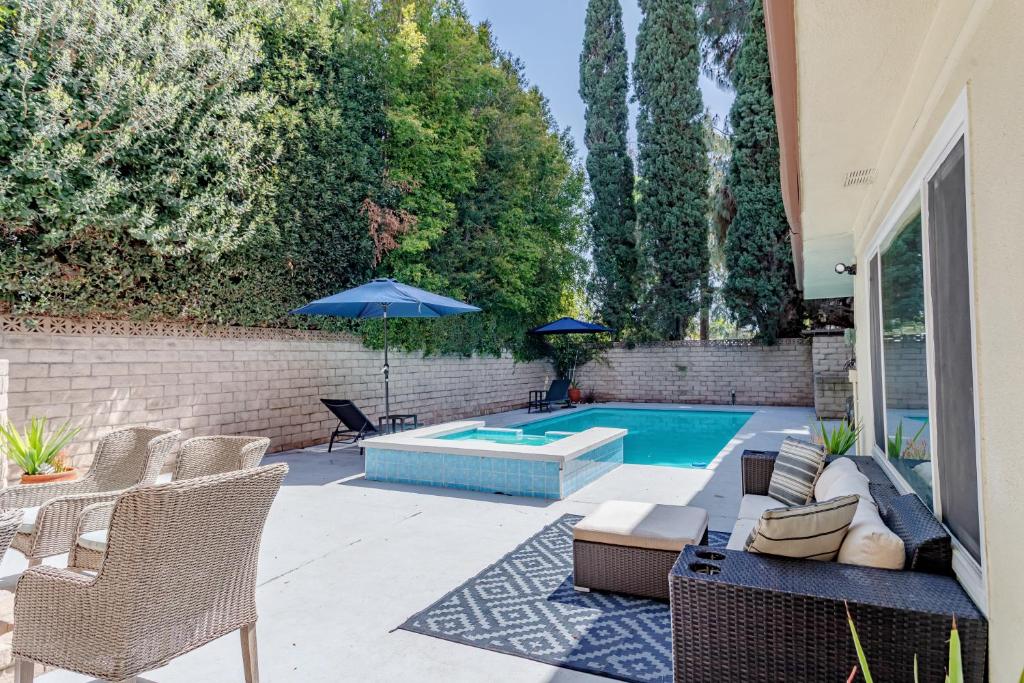 un patio con piscina, sedie e ombrellone di Beautiful 5 bedroom sleeps16 pool Universal a Los Angeles