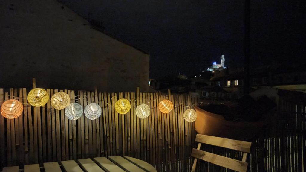 Une bande de lumières sur une clôture en bois la nuit dans l'établissement Le balcon de Montgrand, à Marseille