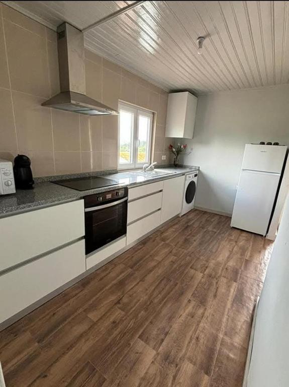 a kitchen with white appliances and a wooden floor at Casa bela paisagem in Castro Daire