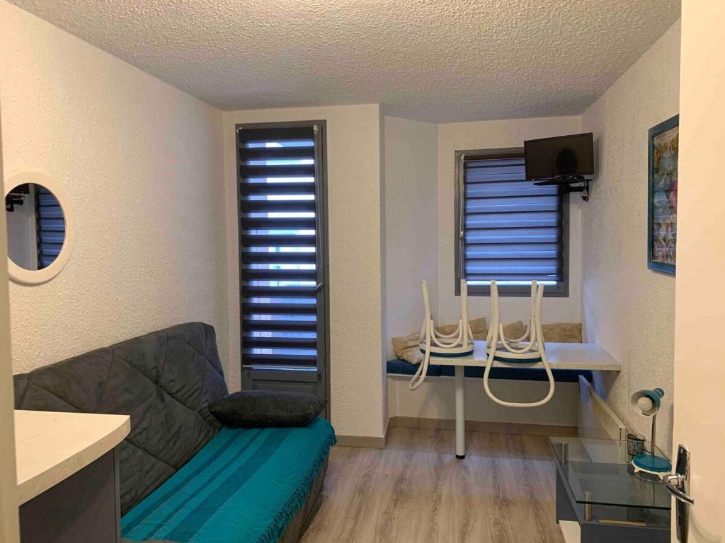 un salon avec un canapé et deux fenêtres dans l'établissement Joli studio Cauterets, à Cauterets