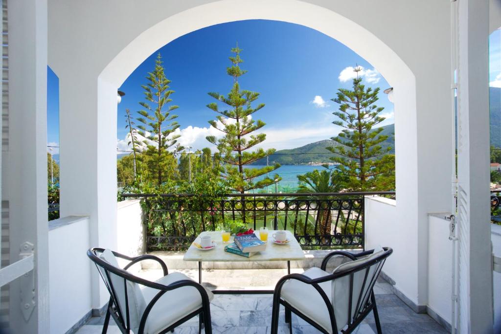 a table and chairs on a balcony with a view of the water at Hotel Athina in Karavomylos