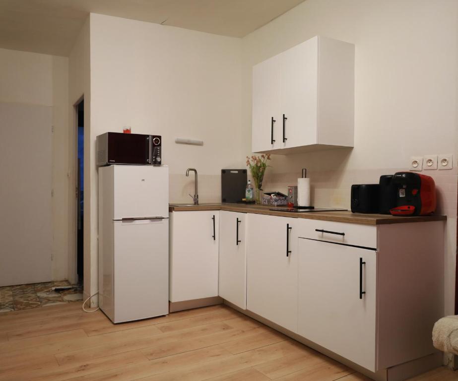 a kitchen with white cabinets and a white refrigerator at Château Rubis T2 hypercentre historique au pied du château in Château-Thierry