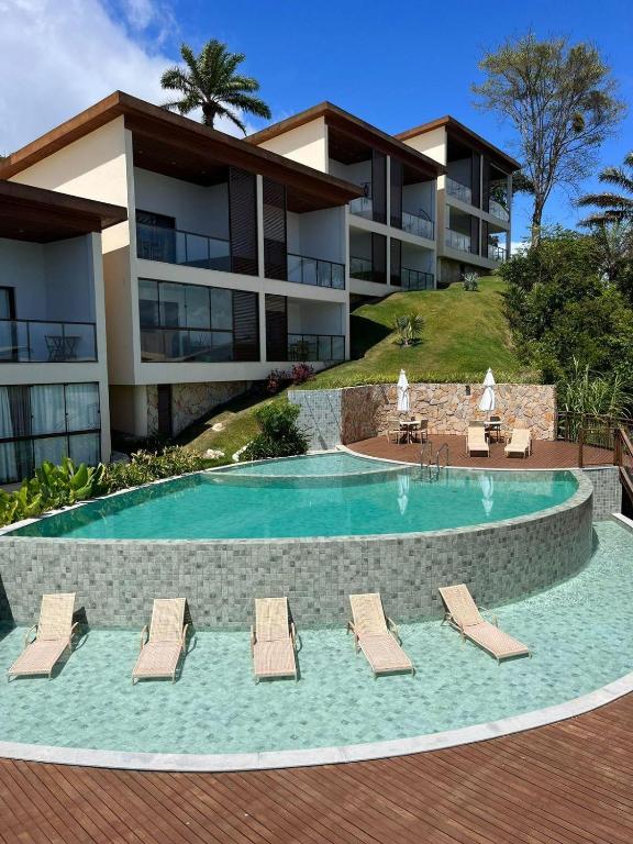 a swimming pool with lounge chairs and a building at Céu do Morro in Morro de São Paulo