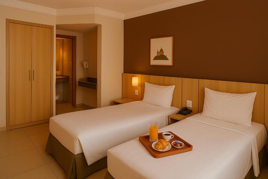 um quarto de hotel com duas camas e uma bandeja de comida em ELEGANCE SUÍTES FRANCA em Franca