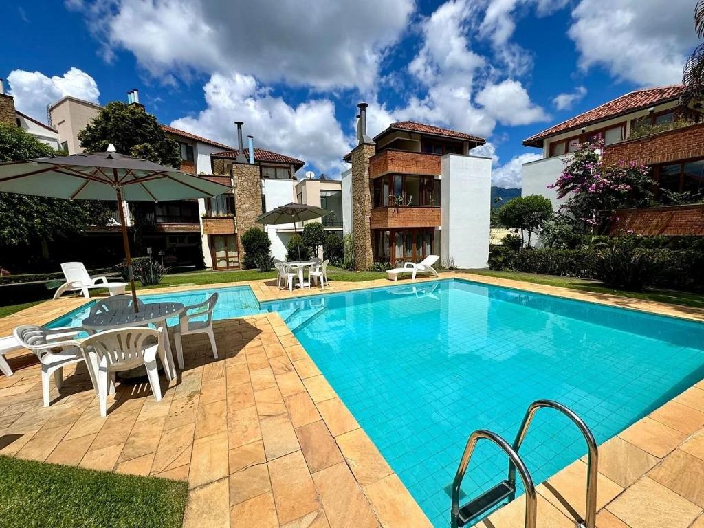 a swimming pool with a table and chairs next to a house at Duplex incrível a 5 min do centro com piscina in Nova Friburgo