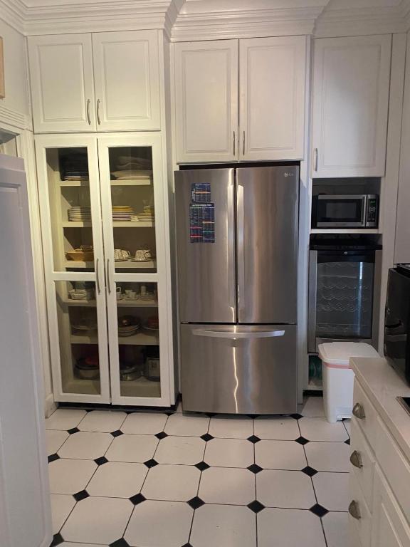a kitchen with white cabinets and a stainless steel refrigerator at Beautiful Villa by the Beach in Nassau