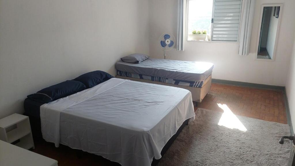 ein Zimmer mit drei Betten und einem Fenster in der Unterkunft Casinha na Vila Madalena in São Paulo