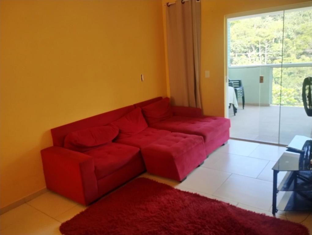 ein rotes Sofa im Wohnzimmer mit einem roten Teppich in der Unterkunft Apartamento completo na praia in Mangaratiba